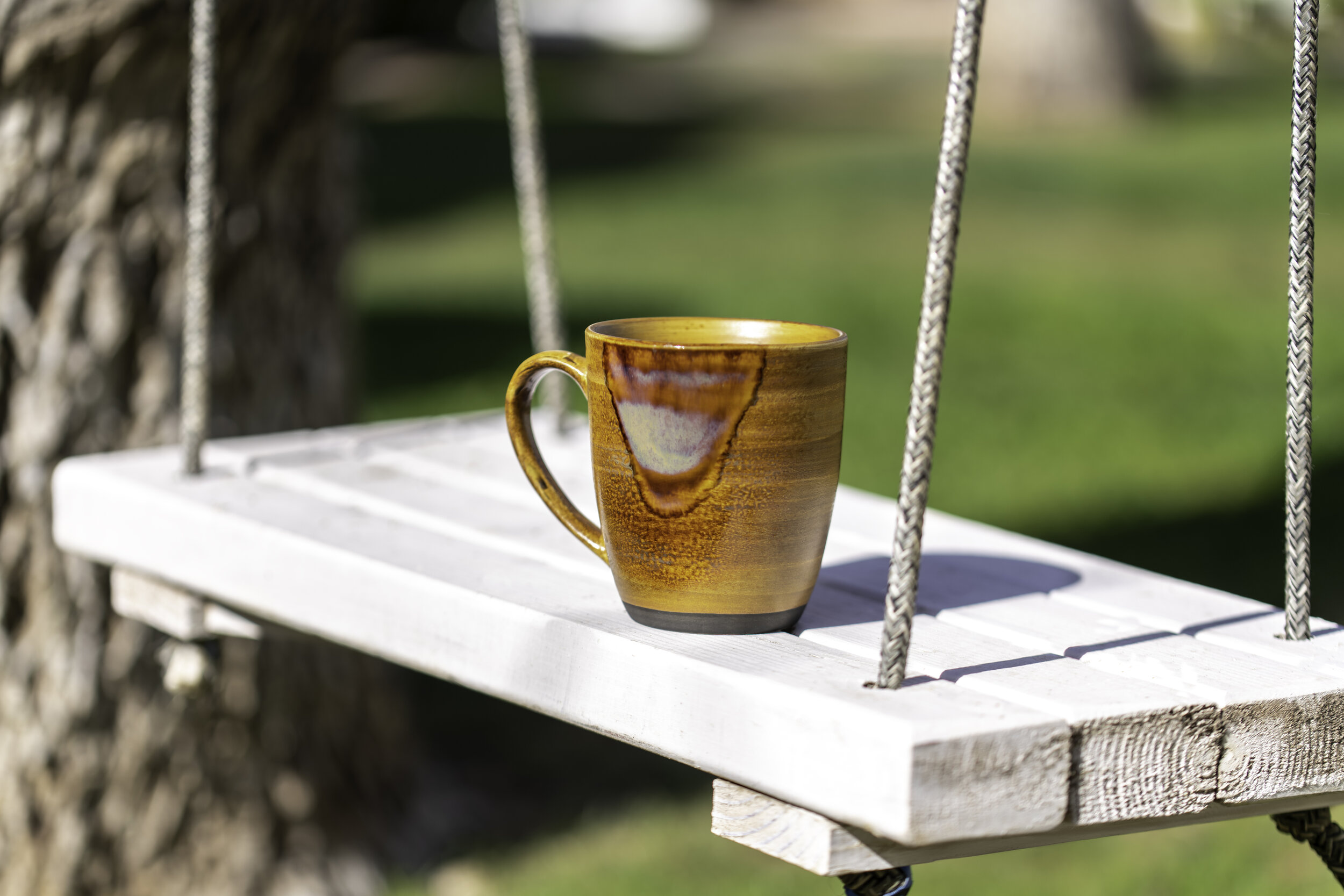 Coffee mug resting on the backyard swing at W2ND Historic Inn
